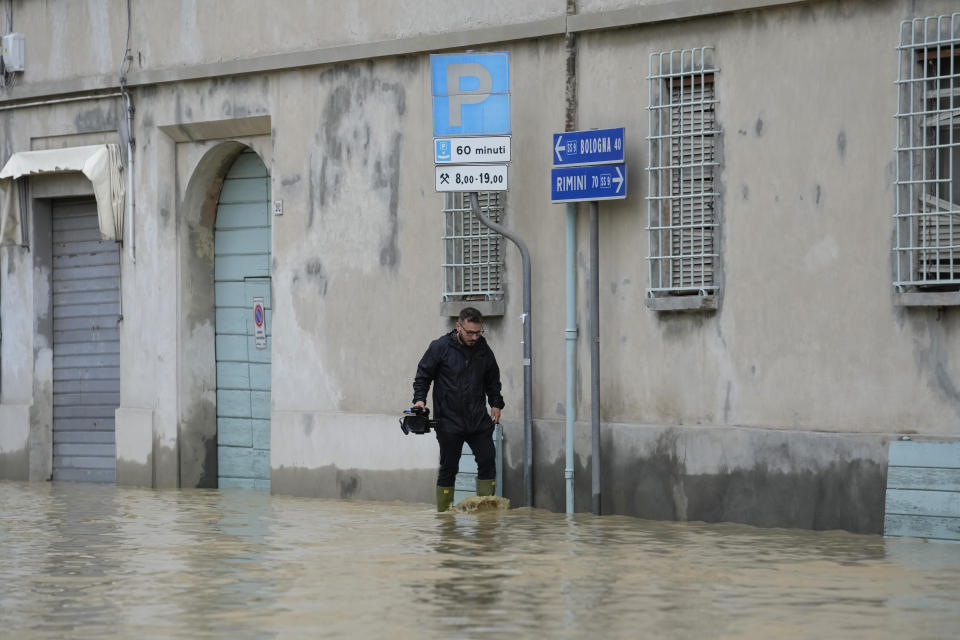 A man walks in a flooded street in the village of Castel Bolognese, Italy, Wednesday, May 17, 2023. Exceptional rains Wednesday in a drought-struck region of northern Italy swelled rivers over their banks, killing at least eight people, forcing the evacuation of thousands and prompting officials to warn that Italy needs a national plan to combat climate change-induced flooding. (AP Photo/Luca Bruno)