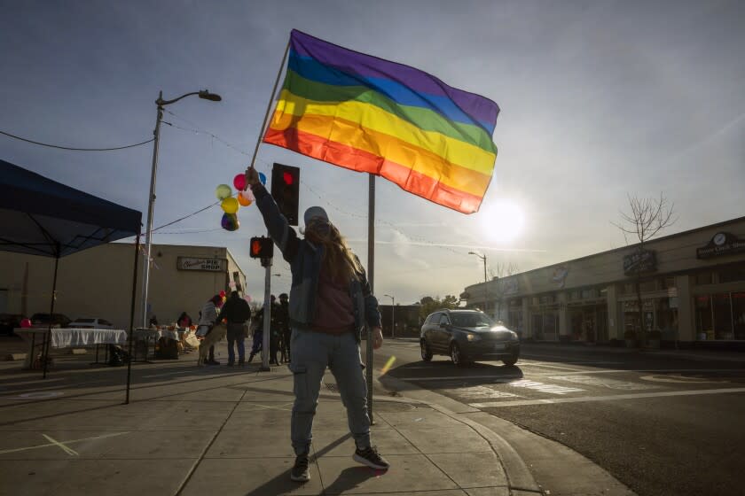 FRESNO, CA FEBRUARY 14, 2021 - Nicole Spate waves a gay pride flag at a gathering of gay and straight community members to protest the recent purchase of the Tower Theater by an evangelical church. Many are concerned in the community that there will be anti-gay sentiment and activity in the small arts community. (Tomas Ovalle / For The Times)