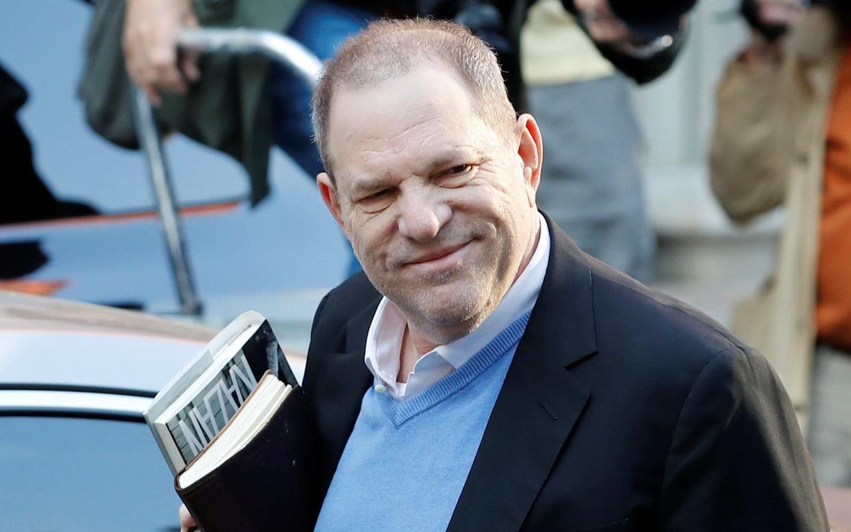 Harvey Weinstein arrives at the Tribeca police station on Friday morning with his books - REUTERS