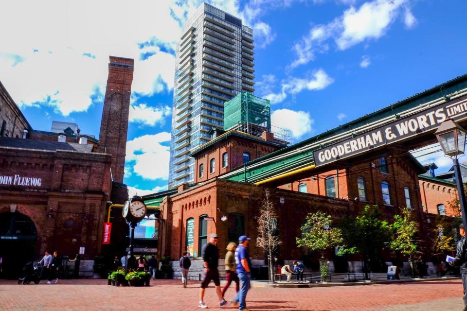 a group of people walking outside in the distillery district of toronto