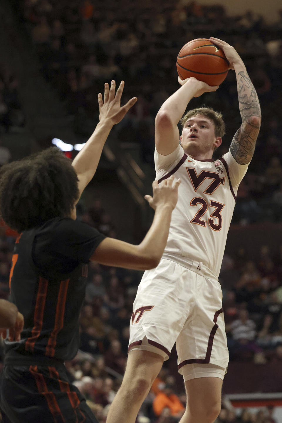 Virginia Tech's Tyler Nickel (23) shoots a 3-point basket while defended by Miami's Michael Nwoko (1) in the first half of an NCAA college basketball game Saturday, Jan. 13, 2024, in Blacksburg, Va. (Matt Gentry/The Roanoke Times via AP)