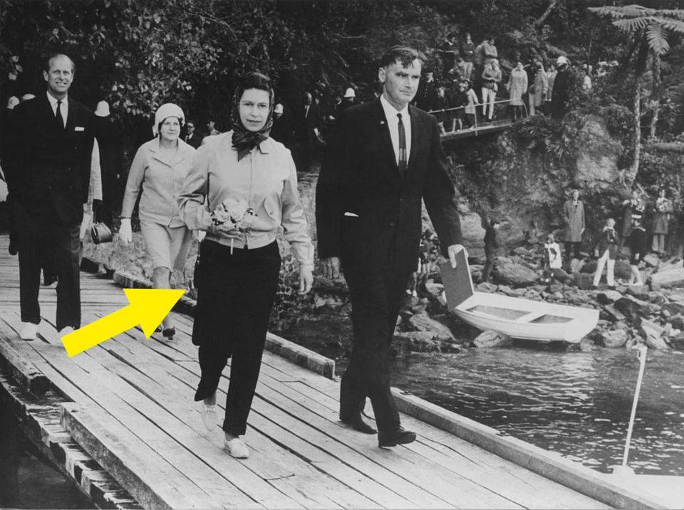 Queen Elizabeth II in pants walking along a pier