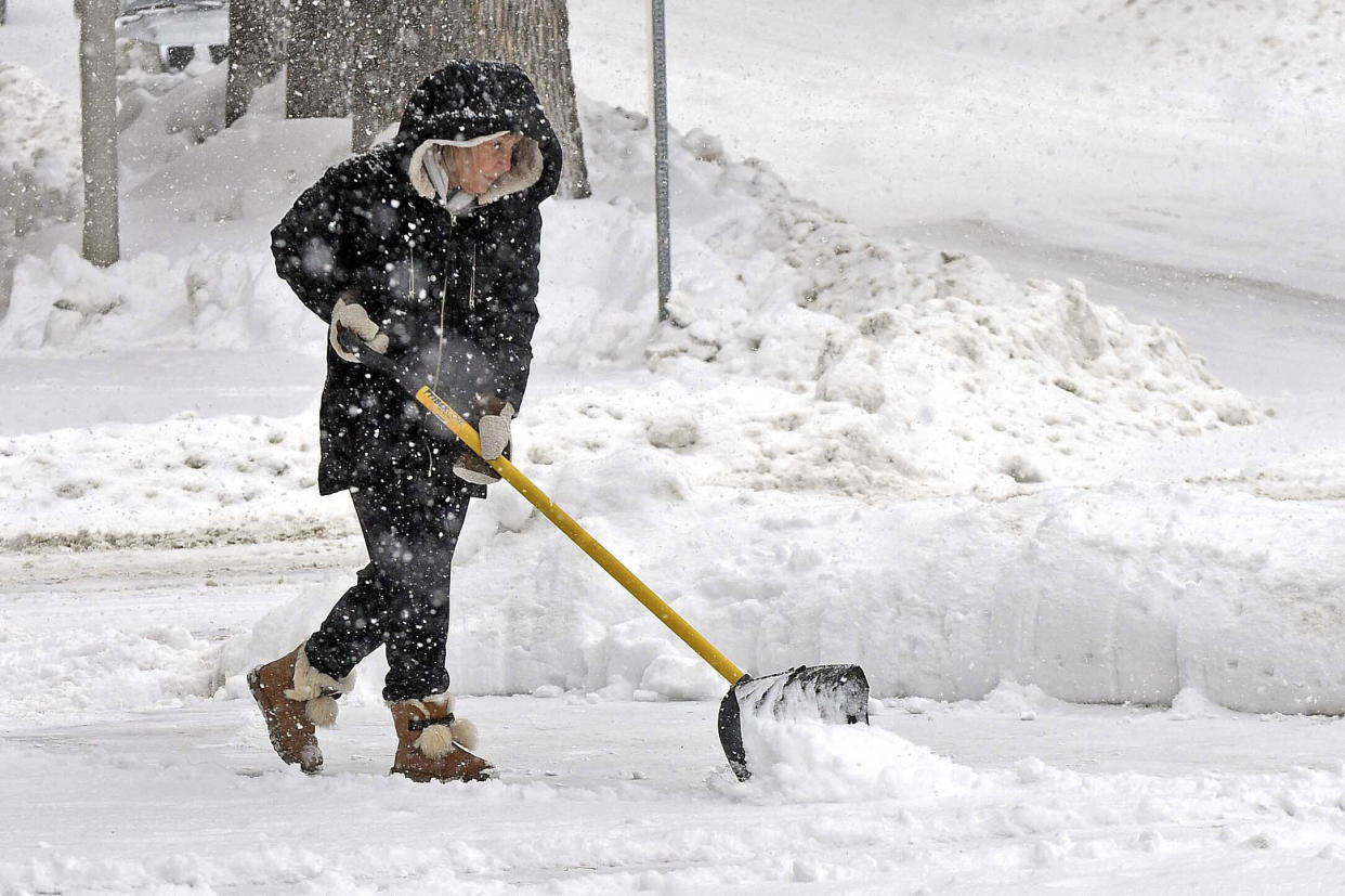 Theresa Kiemele clears a sidewalk in the falling snow outside her business, Westley's Jewelers, in downtown Bismarck, N.D., on Wednesday, Dec. 14, 2022. (Tom Stromme/The Bismarck Tribune via AP)