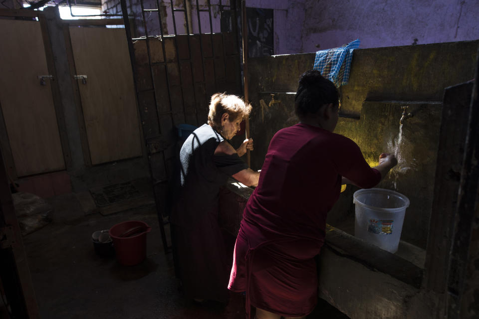 In this March 23, 2020 photo, Maria Isabel Aguinaga washes her clothes in a communal laundry area of a deteriorating building nicknamed “Luriganchito” after the country’s most populous prison, in Lima, Peru. Aguinaga who could no longer afford to pay her rent now lives with her niece Zulema in the sprawling shared home that houses 44 families. (AP Photo/Rodrigo Abd)