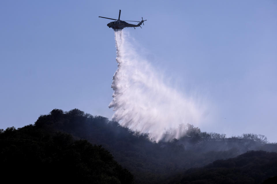 A A helicopter makes a water drop to put out hotspots in a wildfire in Topanga, west of Los Angeles, Monday, July 19, 2021. A brush fire scorched about 15 acres in Topanga today, initially threatening some structures before fire crews got the upper hand on the blaze, but one firefighter suffered an unspecified minor injury. (AP Photo/Ringo H.W. Chiu)