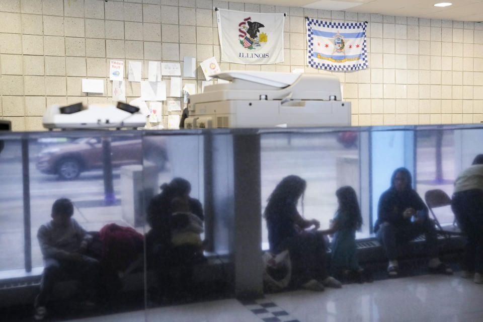 FILE - Immigrants from Venezuela are reflected in a marble wall while taking shelter at the Chicago Police Department's 16th District station on May 1, 2023. Five mayors from around the U.S. want a meeting with President Joe Biden to ask for help controlling the continued arrival of large groups of migrants to their cities. The mayors of Denver, Chicago, Houston, New York and Los Angeles say in a letter to Biden that there has been little to no coordination, support or resources and that is leading to a crisis. (AP Photo/Charles Rex Arbogast, FIle)