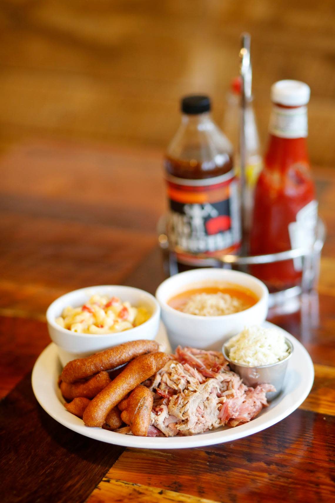 The Pulled Pork Plate at Picnic is served here with slaw, hushpuppies, pimento mac & cheese and smoked tomato gazpacho with bread crumbs.