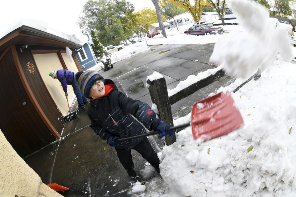 Garrett Simons, 7, helps his grandfather, Dave Salter, shovel snow from the driveway and sidewalks from his home, Friday, Oct. 11, 2019 in Bismarck, N.D. North Dakota Gov. Doug Burgum on Friday activated the state's emergency plan due to what he called a crippling snowstorm that closed major highways and had farmers and ranchers bracing for the potential of huge crop and livestock losses. (Mike McCleary/The Bismarck Tribune via AP)