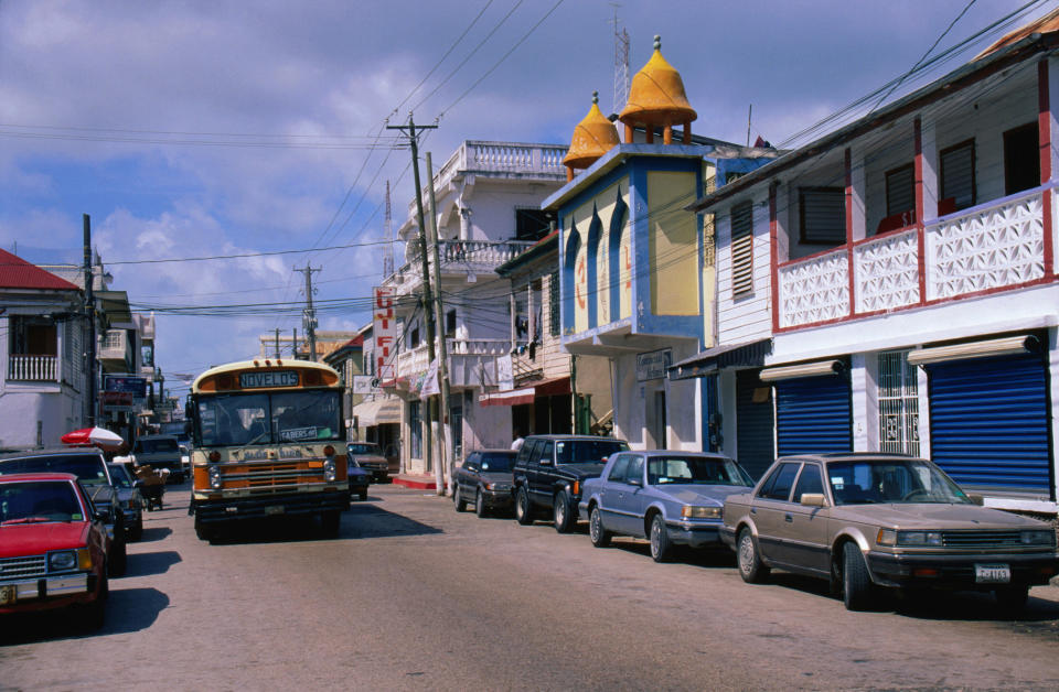 a street in belize city with a bus going down the road