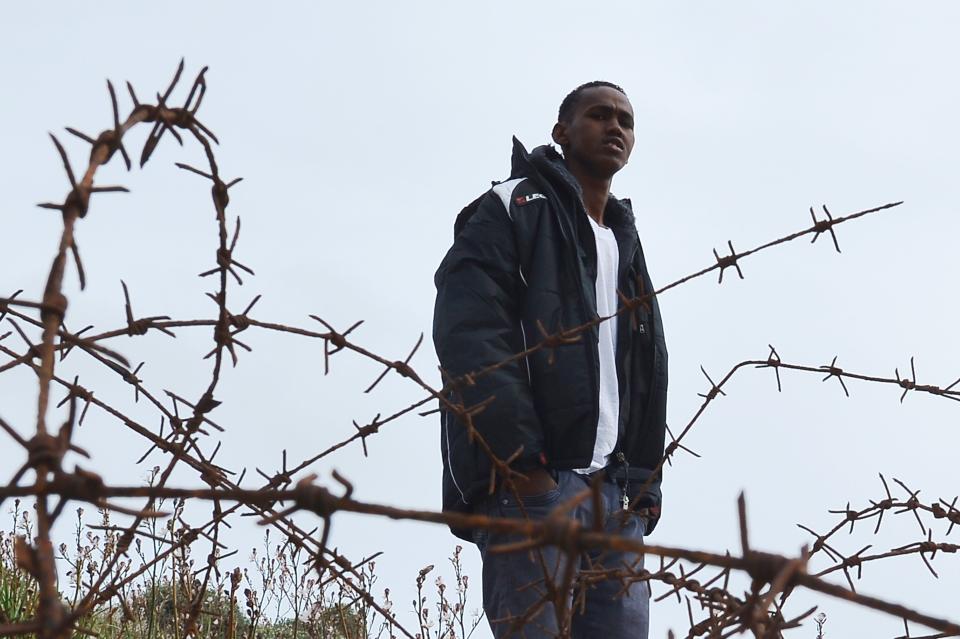 A young migrant makes a walk outside the 'Temporary Permanence Centre' (CPT), a refugee camp on the Lampedusa island on February 19, 2015. Authorities on the Italian island of Lampedusa struggled to cope with a huge influx of newly-arrived migrants as aid organisations warned the Libya crisis means thousands more could be on their way. Officials on the tiny island south of Sicily were trying to process more than 1,200 exhausted, often traumatised and ill Africans in a reception centre designed for less than a third of that number.  AFP PHOTO / ALBERTO PIZZOLI        (Photo credit should read ALBERTO PIZZOLI/AFP/Getty Images)