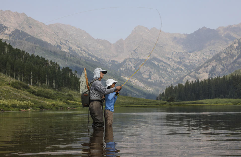 Robert Yi teaches his daughter Sylvana, 11, of Evergreen, how to fly fish, Sunday, July 25, 2021, at Piney Lake outside of Vail, Colo. The lake is a popular destination for many recreational activities. (Chris Dillmann/Vail Daily via AP)