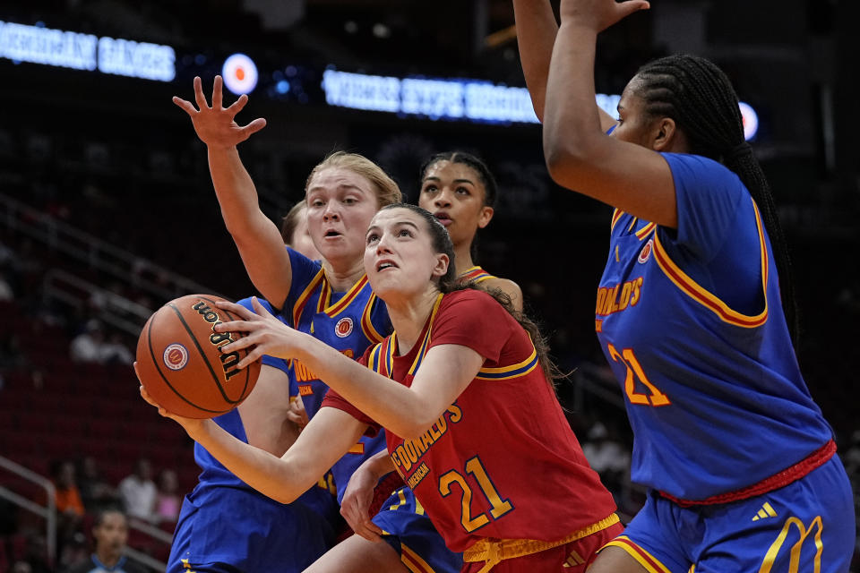 West guard Morgan Cheli (21) drives between East guard Olivia Olson, left, and East forward Sarah Strong, right, during the first quarter of the McDonald's All American girls' basketball game Tuesday, April 2, 2024, in Houston. (AP Photo/Kevin M. Cox)