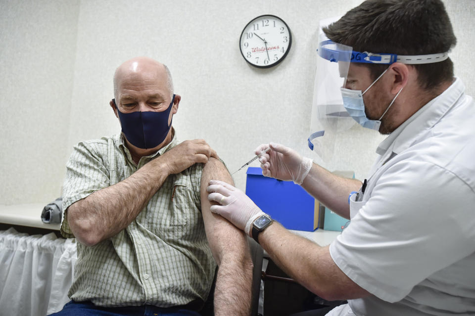 FILE - In this April 1, 2021 file photo, Montana Gov. Greg Gianforte receives a shot of the Pfizer COVID-19 vaccine from pharmacist Drew Garton at a Walgreen's pharmacy in Helena, Mont. While large companies across the U.S. have announced that the COVID-19 vaccine will be required for their employees to return to work in-person, there is one state where such requirements are banned: Montana. Under a new law passed by the Republican-controlled Montana Legislature earlier this year, requiring vaccines as a condition for employment is deemed “discrimination” and a violation of the state’s human rights laws.(Thom Bridge/Independent Record via AP, File)