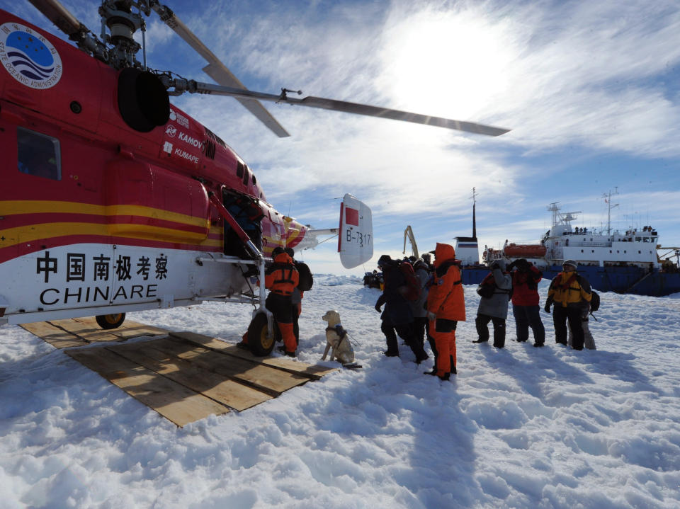 In this photo provided China's official Xinhnua News Agency, passengers from the trapped Russian vessel MV Akademik Shokalskiy, seen at right, prepare to board the Chinese helicopter Xueying 12 in the Antarctic Thursday, Jan. 2, 2014. A helicopter rescued all 52 passengers from the research ship that has been trapped in Antarctic ice, 1,500 nautical miles south of Hobart, Australia, since Christmas Eve after weather conditions finally cleared enough for the operation Thursday. (AP Photo/Xinhua, Zhang Jiansong) NO SALES