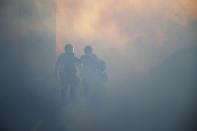 Authorities move through an area filled with tear gas Thursday, May 28, 2020, in St. Paul, Minn. Protests over the death of George Floyd, a black man who died in police custody, broke out in Minneapolis for a third straight night. (AP Photo/John Minchillo)