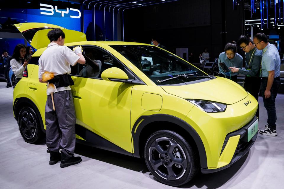 People use their phones in front of the BYD Seagull that is displayed at the Auto Shanghai show, in Shanghai, China April 19, 2023.