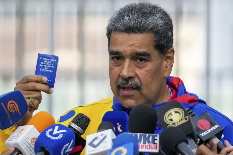 El presidente Nicolás Maduro muestra una miniedición de la constitución de Venezuela después de votar en las elecciones presidenciales en Caracas, Venezuela, el domingo 28 de julio de 2024. (AP Foto/Fernando Vergara)