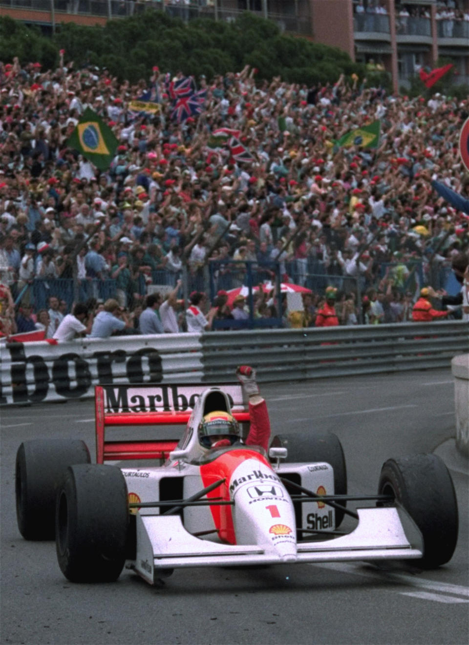 FILE - In this May 31, 1992 file photo, Brazilian driver Ayrton Senna raises his fist to salute the crowd after he won the Monaco Formula One Grand Prix on his McLaren-Honda. Brazil’s adoration of Ayrton Senna transcends sports. Senna won three Formula One titles — in 1988, 1990 and '91 — all with McLaren. He moved to the Williams team for his tragic 1994 season. Despite his career being cut short when he was 34, his 41 wins stand third all-time behind Michael Schumacher's 91 and rival Alain Prost's 51. He died at the 1994 San Marino Grand Prix. (AP Photo/JEAN-MARC FOLLETE, File)