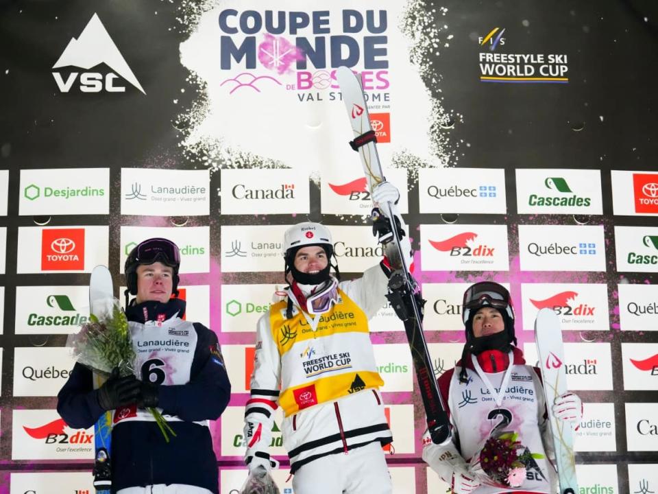 Canadian freestyle skier  Mikaël Kingsbury, middle, celebrates his World Cup moguls win alongside silver medallist Walter Wallberg of Sweden, left, and bronze medallist Ikuma Horishima of Japan on Friday in Saint-Côme, Que. (Sean Kilpatrick/The Canadian Press - image credit)