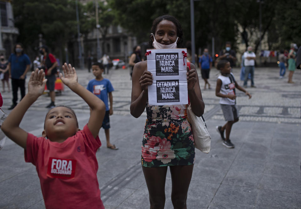 A woman holds a sign with a message that reads in Portuguese: "Dictatorship never again," during a protest against the Brazilian President Jair Bolsonaro coinciding with the anniversary of the 1964 military coup that established a decades-long dictatorship, at Cinelandia square in Rio de Janeiro, Brazil, Wednesday, March 31, 2021. The leaders of all three branches of Brazil’s armed forces have jointly resigned following Bolsonaro’s replacement of the defense minister, that is causing widespread apprehension of a military shakeup to serve the president’s political interests. (AP Photo/Silvia Izquierdo)