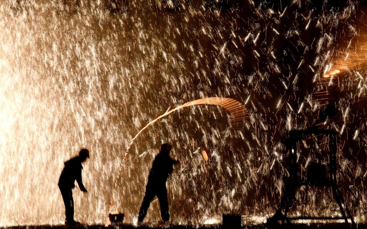 HANDAN, CHINA - JANUARY 19, 2020 - Craftsman in "fighting iron flower", Handan City, Hebei Province, China, on the evening of January 19, 2020. "Beating iron flower" is a scene of "iron flower fire rain" in the air after turning pig iron into molten iron with a small iron smelting furnace, and then beating the molten iron with sawdust on the sky with a board. - PHOTOGRAPH BY Costfoto / Barcroft Media (Photo credit should read Costfoto / Barcroft Media via Getty Images)