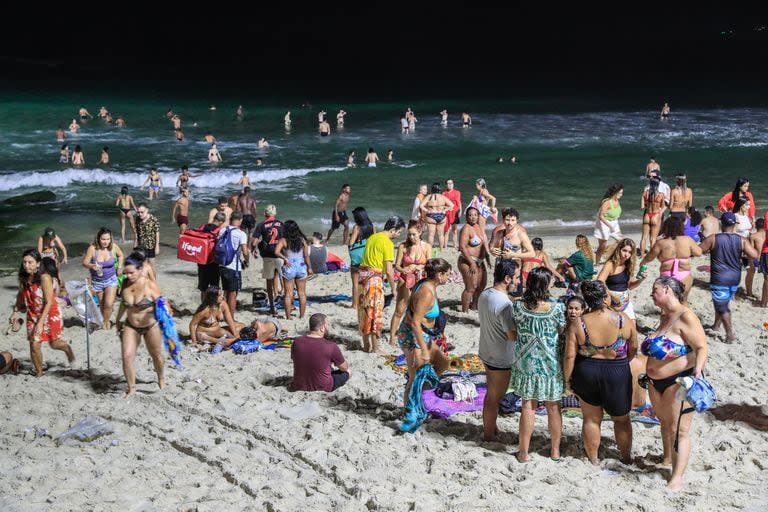 Las personas se bañan a la noche en la playa de Arpoador en Río de Janeiro por las altas temperaturas
