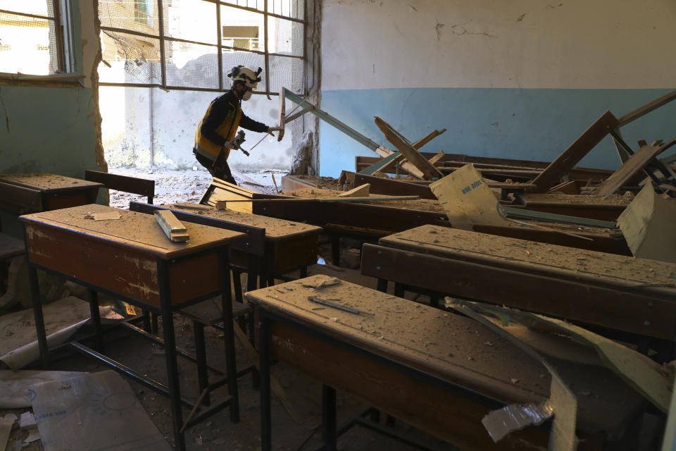 This photo provided by the Syrian Civil Defense White Helmets, which has been authenticated based on its contents and other AP reporting, shows a Syrian White Helmet civil defense worker checking a school classroom damaged by shelling in the town of Afrin, north of Aleppo, Thursday, Jan. 20, 2022. The rocket attack on Afrin, controlled by Turkey-backed opposition fighters, killed several civilians and wounded over a dozen people on Thursday, Syrian rescuers and a war monitor said. Both blamed U.S-backed Syrian Kurdish forces for the attack. (Syrian Civil Defense White Helmets via AP)