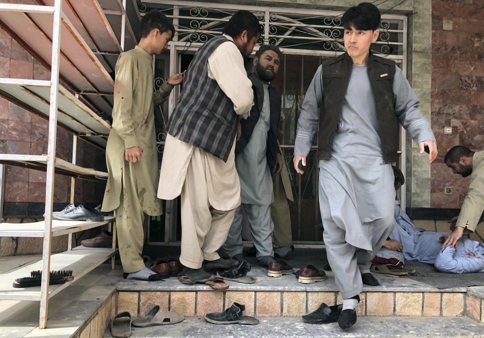An injured man, right, is tended after a bomb blast in Mazar-e-Sharif, the capital city of Balkh province, in northern Afghanistan, Saturday, March 11, 2023. A bomb exploded on Saturday during an award ceremony for journalists in the city. (AP Photo/Abdul Saboor Sirat)