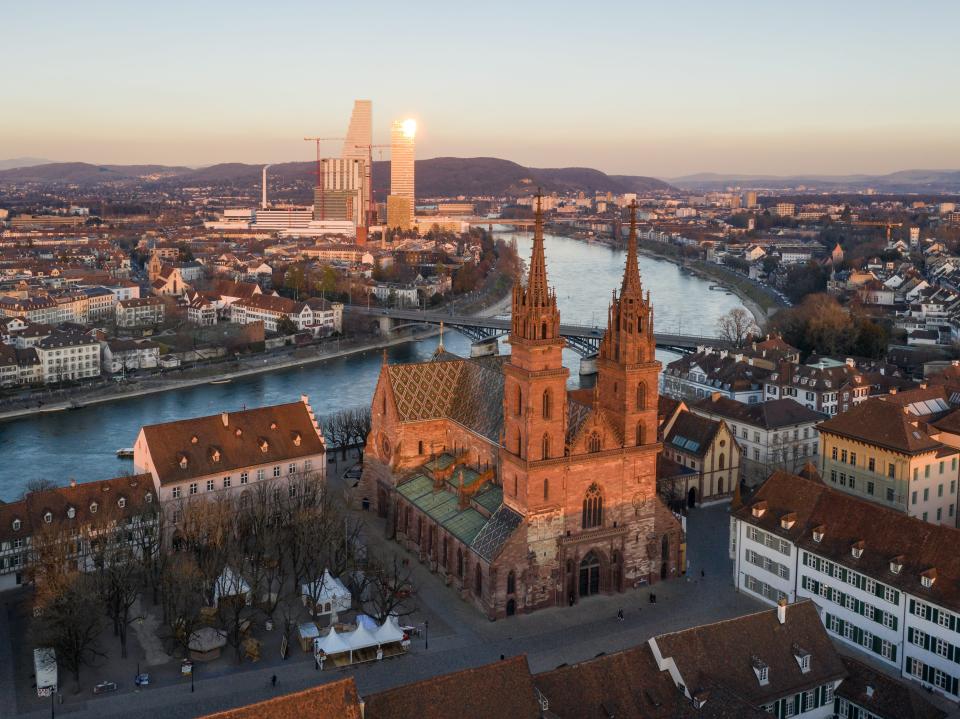 Aerial view of the Basel medieval old town with its cathedral along the Rhine river with modern officel buildings in the background, in Switzerland