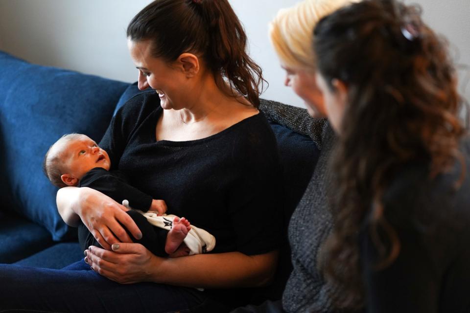 (Left to right) Detroit Doulas co-owner Kirsten Johnson holds 6-week-old Sawyer Basin as she talks with his mothers Alicia Basin and Corinne Rockoff during a post-natal visit to a family at their home in Ferndale on January 13, 2023.