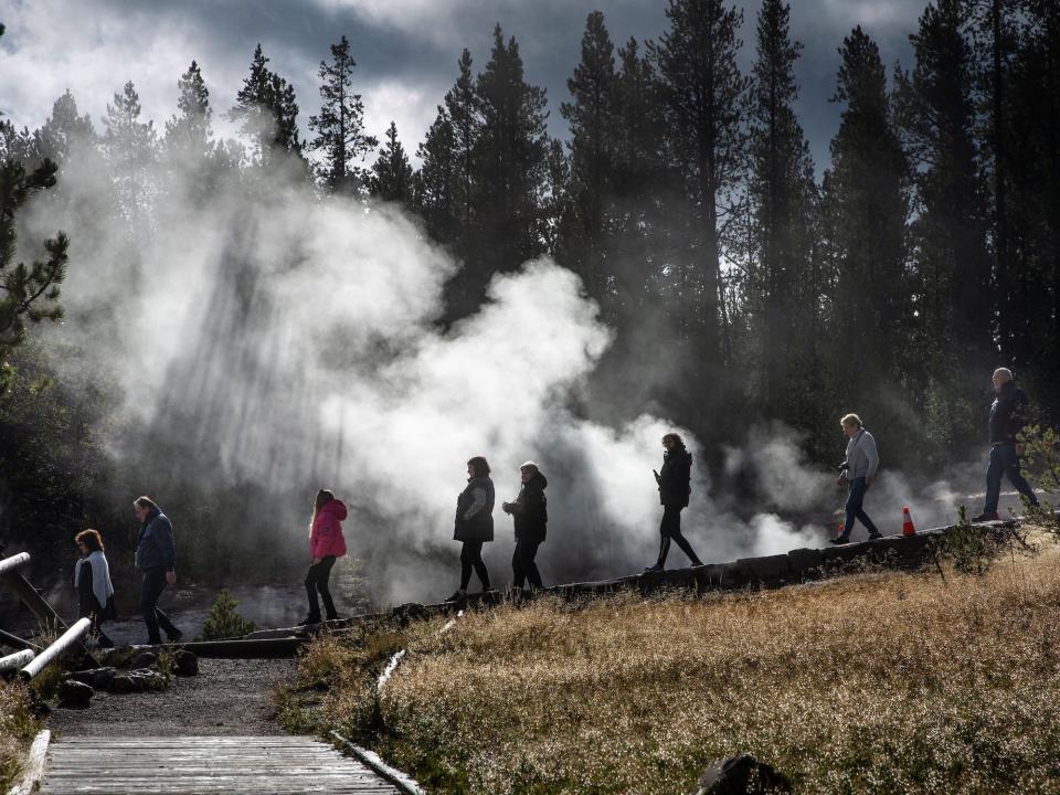 Hikers walk by steam vents and hot springs in the Norris Basin in Yellowstone National Park, Wyoming, on September 23, 2022.