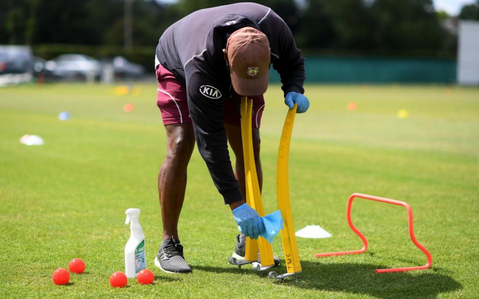 A cricket coach cleans equipment during a junior training session - GETTY IMAGES