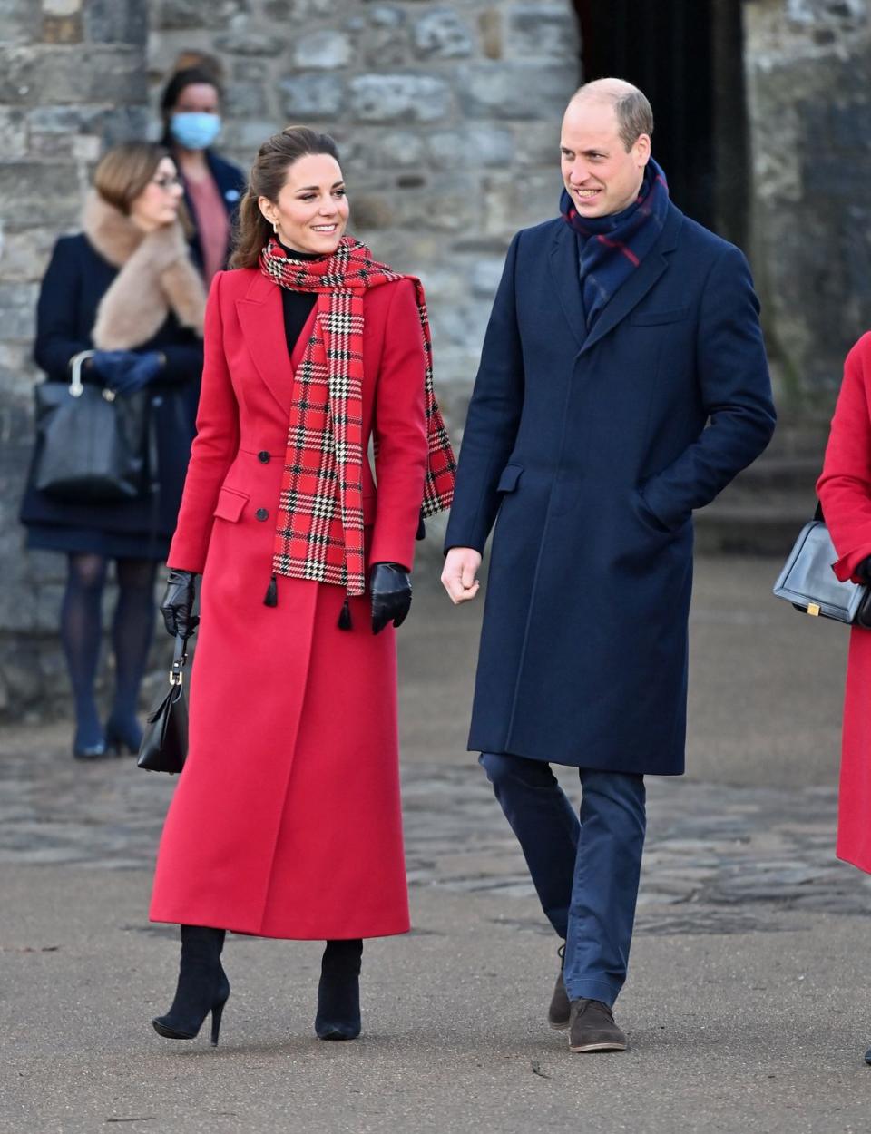 <p>While on their royal train tour to thank transport workers in London, the duchess wore a festive red wool coat with a plaid scarf and black suede boots.</p>