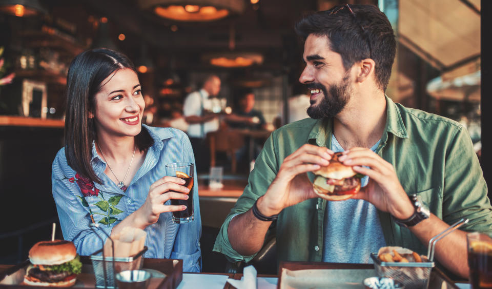 A man and woman eating hamburgers in a restaurant.