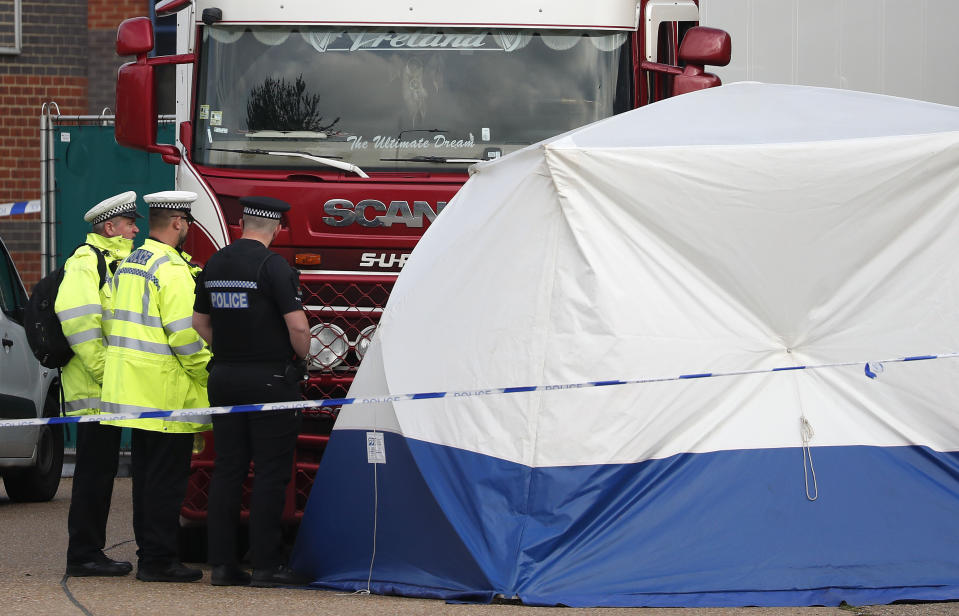 Police officers attend the scene after a truck was found to contain a large number of dead bodies, in Thurrock, South England, early Wednesday Oct. 23, 2019. Police in southeastern England said that 39 people were found dead Wednesday inside a truck container believed to have come from Bulgaria. (AP Photo/Alastair Grant)