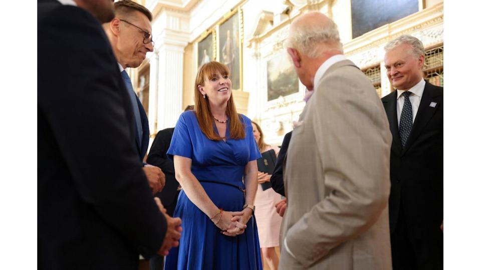 King Charles in a grey suit talking to Angela Rayner, who wears a blue dress