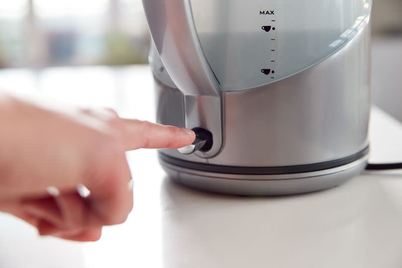 Close Up Of Woman Pressing Power Switch On Electric Kettle To Save Energy At Home