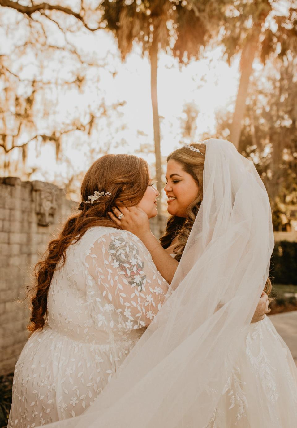 Two brides hold each other and gaze in each other's eyes.