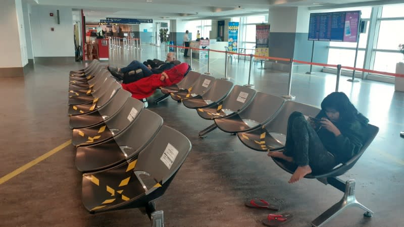 Stranded tourists sit in chairs at the transit area of Kuala Lumpur International Airport in Sepang