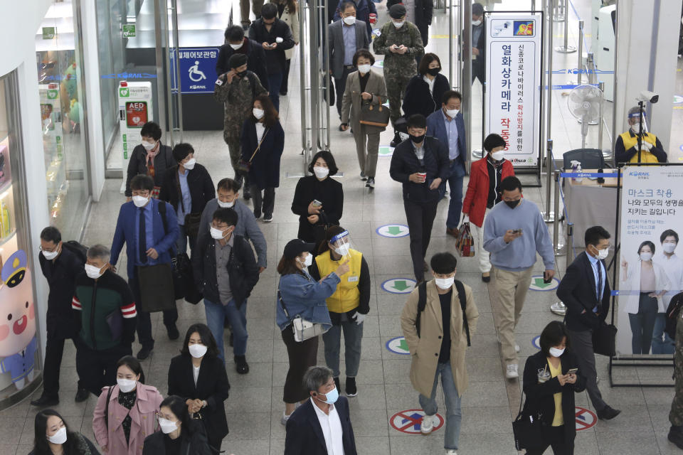 An employee, center right, wearing a face mask and face shield to help protect against the spread of the coronavirus, guides a passenger at the Seoul Railway Station in Seoul, South Korea, Thursday, Oct. 22, 2020. (AP Photo/Ahn Young-joon)