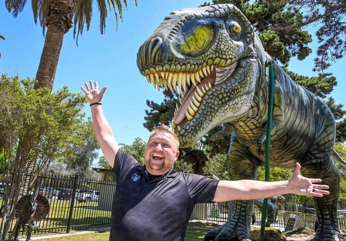 Davey Helm of Helm and Sons Amusements poses with his T-rex at the entrance to Playland in Roeding Park, which has been promised to reopen on June 1.