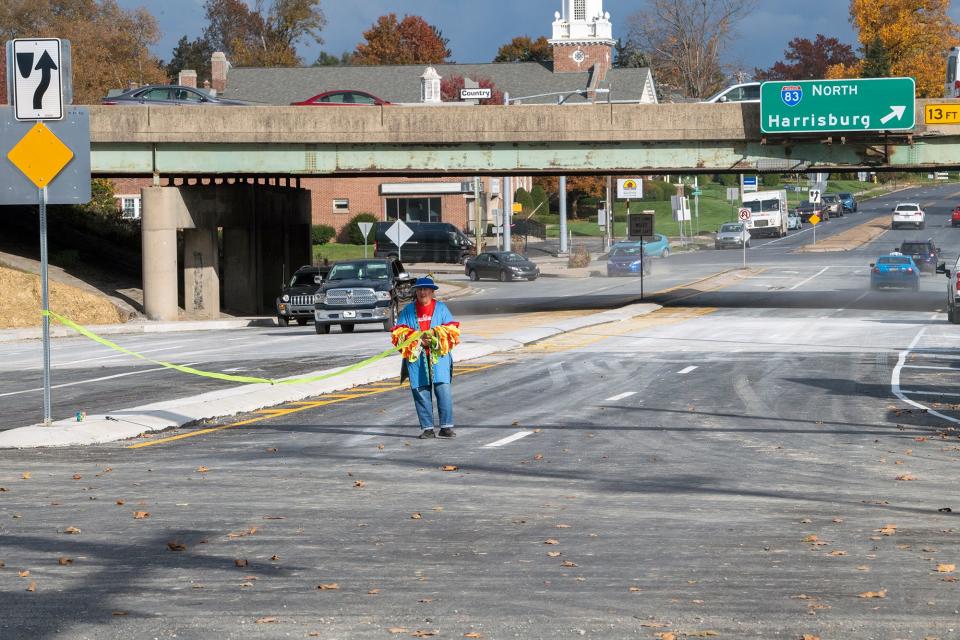 DIta Ziegler, of York, who brought the construction crew cookies during the project, rolls up a ribbon officially marking the opening after traffic started moving across the new bridge on East Market Street Tuesday.