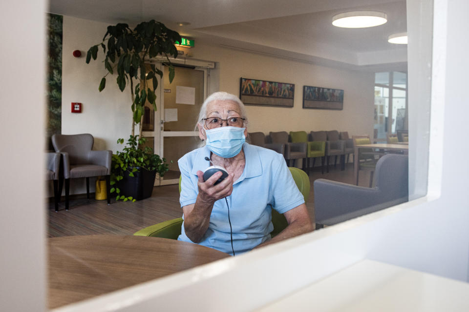 26 June 2020, Hessen, Kassel: Resident Jenny Nelle talks to a visitor via a baby monitor and through a Plexiglas panel in the entrance area of the AWO senior citizens' centre "Käthe-Richter-Haus". Since one week residents of old people's and nursing homes are allowed to have more visitors again. (to dpa "More visitors in homes: blessing and risk factor") Photo: Swen Pförtner/dpa (Photo by Swen Pförtner/picture alliance via Getty Images)