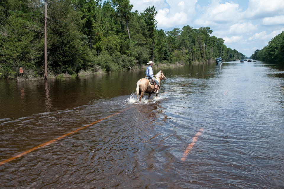 A man rides a horse through flooded streets.