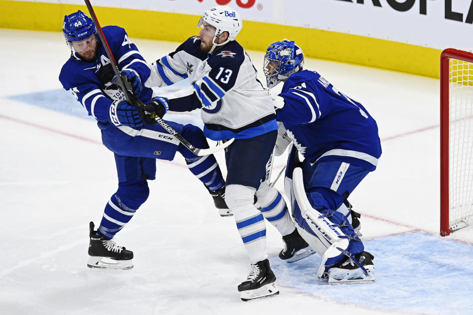 Toronto Maple Leafs goaltender Frederik Andersen (31) tries to look around a battle between Winnipeg Jets center Pierre-Luc Dubois (13) and Maple Leafs defenseman Morgan Rielly (44) during first-period NHL hockey game action in Toronto, Saturday, March 13, 2021. (Frank Gunn/The Canadian Press via AP)