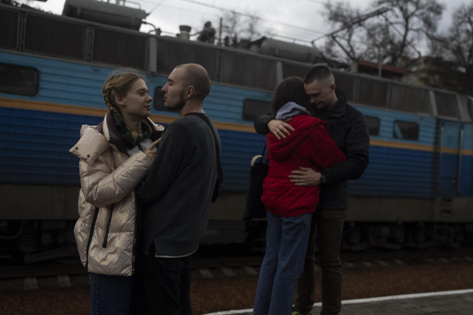 Vlad 27, second left, and Vlad 25, right, say goodbye to their girlfriends Elizabet 23, left, and Sofia 25 at the train station in Odesa, southern Ukraine, on Saturday, April 2, 2022. Elisabet and Sofia are fleeing the war in Ukraine to Poland. (AP Photo/Petros Giannakouris)