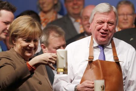 German Chancellor Angela Merkel and Hesse's state Premier Volker Bouffier (R) toast with beer during the Christain Democratic Union (CDU) politial Ash Wednesday meeting in Volkmarsen, Germany February 29, 2016. REUTERS/Kai Pfaffenbach/File Photo