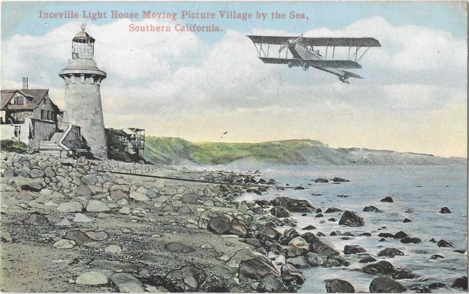 A lighthouse on a rocky coast, with a biplane flying past