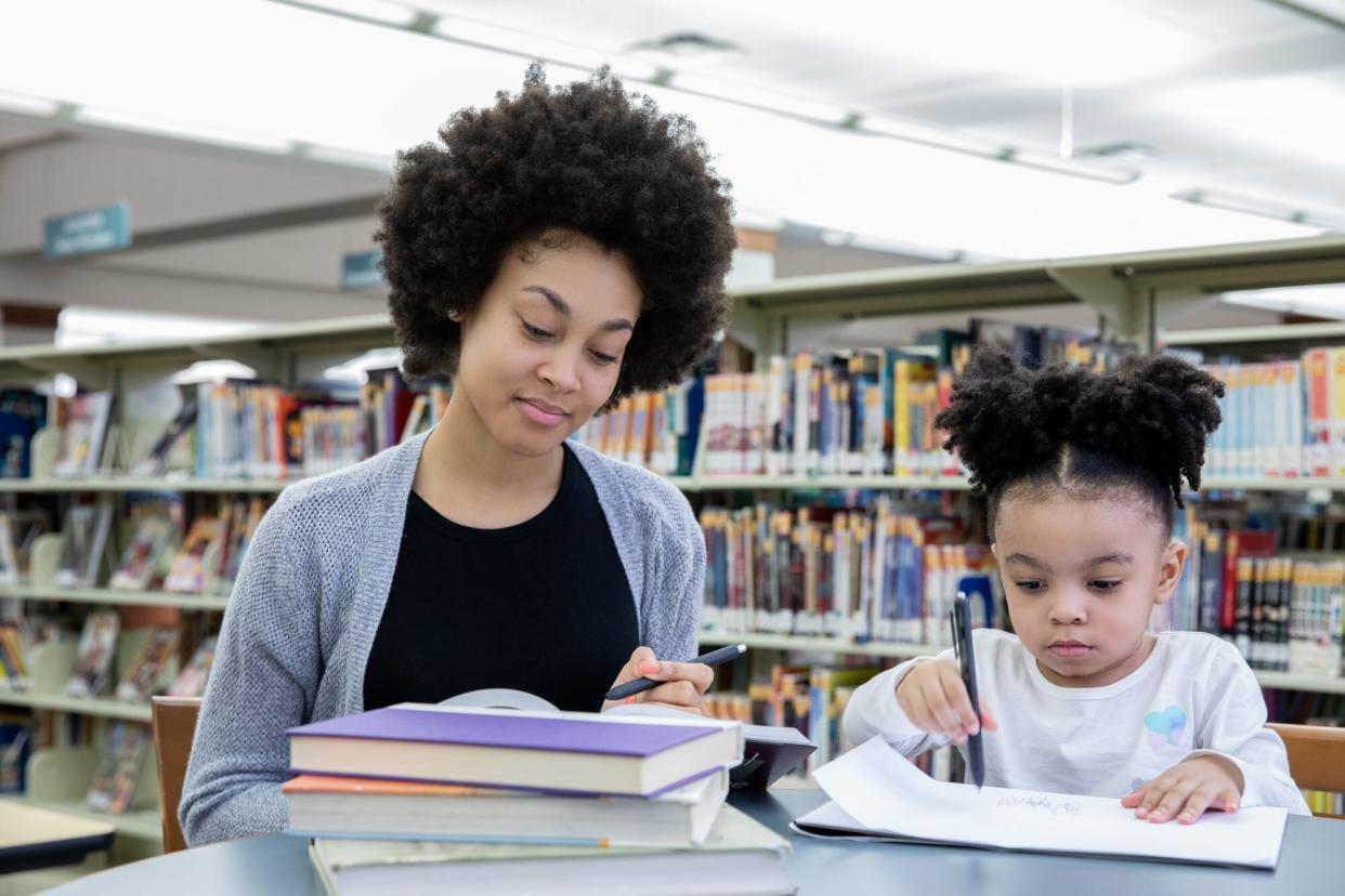 Mother studying in library with toddler daughter
