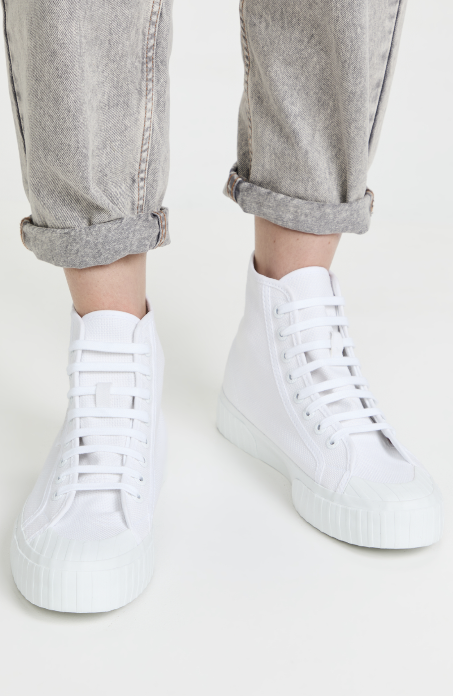 woman wearing light grey jeans and white Superga 2696 Stripe Hightop Sneakers (Photo via Shopbop)